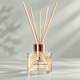 Diffuseur de parfum d’ambiance Miaou Candle 100 ml en verre transparent, bouchon rosé et tiges naturelles sur fond gris-vert