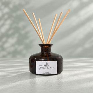 Diffuseur de parfum d’ambiance Miaou Candle 200 ml en verre ambré avec six tiges naturelles sur fond sauge